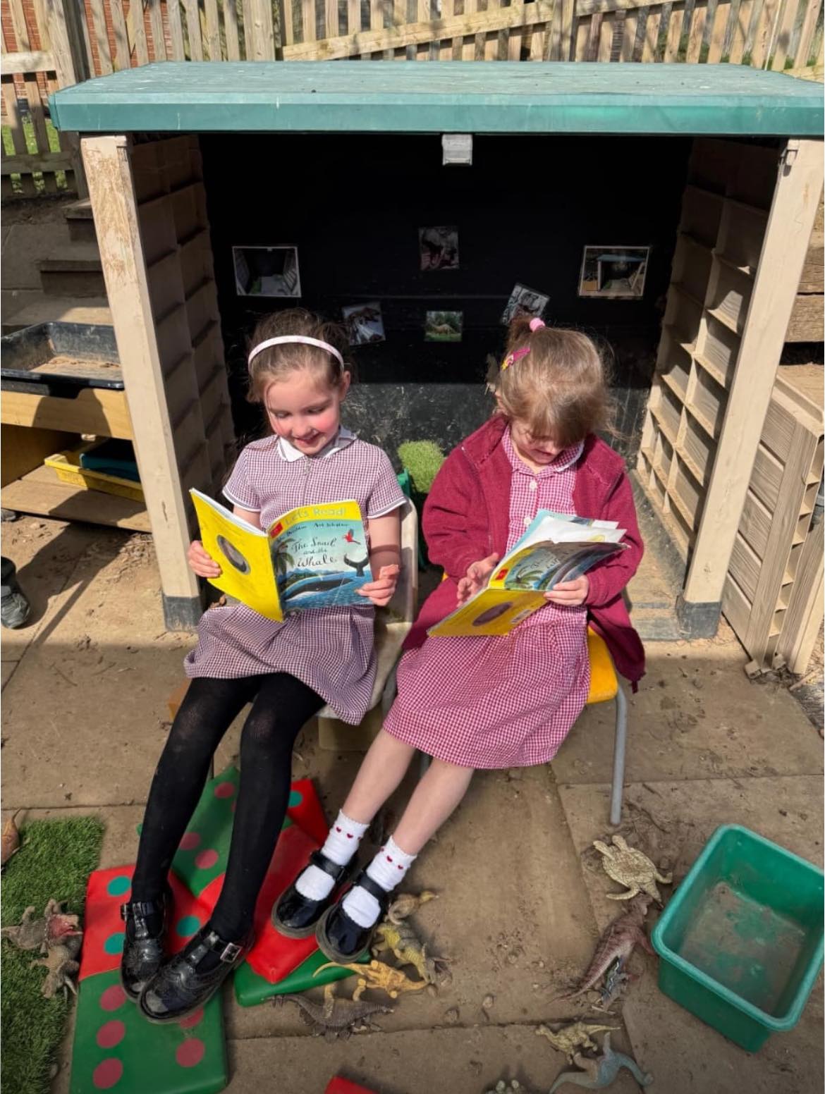 two children in Kilsby uniform reading books in an outdoor area